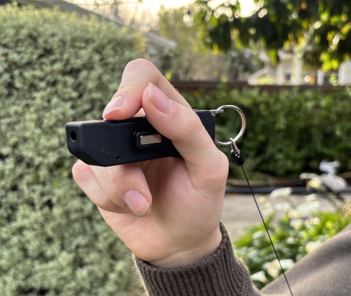 A person holds a Glance prototype in one hand, with a finger resting on its button.