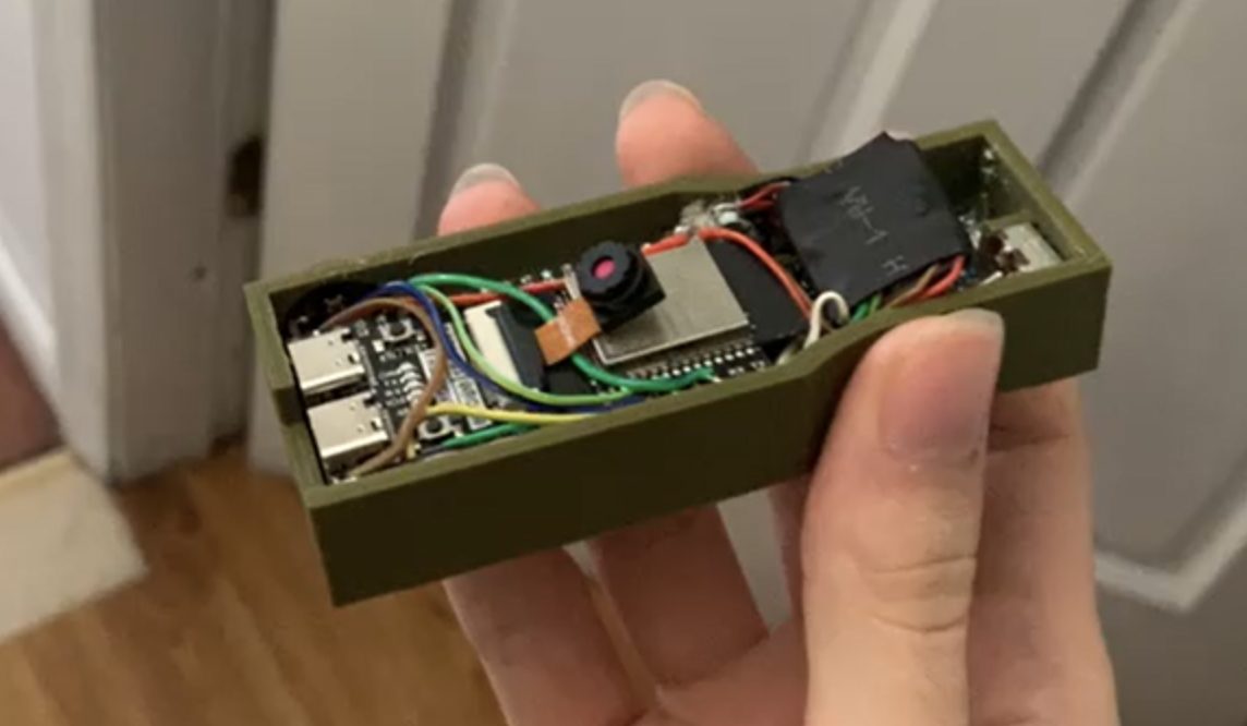 Video of the Gen 0.1 prototype working. The photo shows a hand holding its open, green 3D-printed case, with a camera, circuit boards and wiring inside.